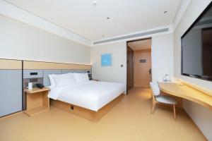 a bedroom with a large white bed and a flat screen tv at JI Hotel Shenzhen Huaqiang North Huaqiang Road Subway Station in Shenzhen