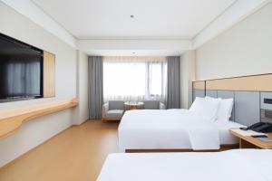 a hotel room with two beds and a flat screen tv at JI Hotel Shenzhen Huaqiang North Huaqiang Road Subway Station in Shenzhen
