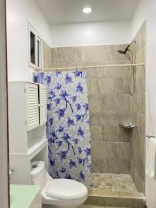 a bathroom with a shower with a blue and white shower curtain at Onat Roatan Casa in West End