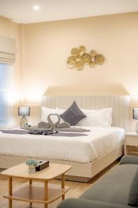a bedroom with a large white bed and a table at Treerat Bangtao House in Ban Hua Phrong