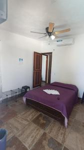 una camera da letto con un letto viola con un ventilatore a soffitto di Casa Rústica, Sofía, Frente al mar en Puerto Arista a Puerto Arista Altre 11 foto