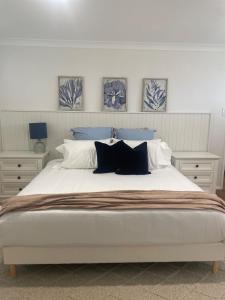 a bedroom with a large white bed with blue pillows at Coastal play and stay - walk to beach and park in Toowoon Bay