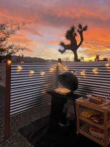 ein Grill vor einem Zaun mit einer Palme in der Unterkunft Zenity Joshua tree in Joshua Tree