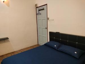 a bedroom with a blue bed and a white door at BENUTHOMEStay in Benut
