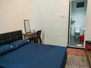 a bedroom with a blue bed and a desk and a bathroom at BENUTHOMEStay in Benut