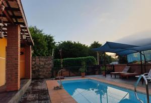 a swimming pool with a blue umbrella next to a house at DON MIGUEL DEPARTAMENTOS in Puerto Iguazú +8 photos