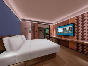 a bedroom with a white bed and a flat screen tv at Orange Hotel Shenzhen Nanshan Subway Station in Shenzhen