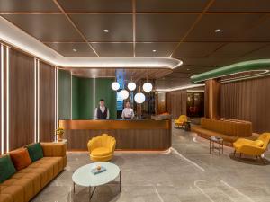 a lobby with a bar and two people standing at a counter at Orange Hotel Shenzhen Nanshan Subway Station in Shenzhen
