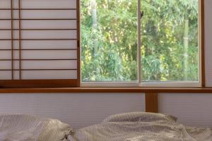 伊东Ito Orange Beach Villa - Ocean View & Private Onsen的窗户,带一张床和枕头