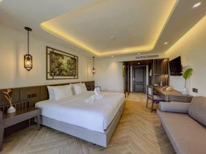 a bedroom with a bed and a desk and a couch at Peach Hill Resort - SHA Extra Plus in Kata Beach +64 photos