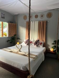 a bedroom with a swinging bed with a white bedspread at The Bangka Beach Guesthouse in Siquijor