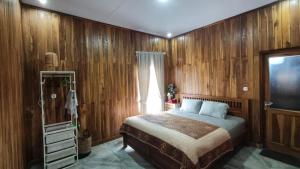 a bedroom with wooden walls and a bed and a television at Villa Bella Sembalun in Sembalun Lawang