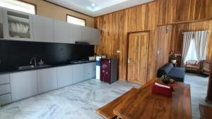 a kitchen with white cabinets and a wooden wall at Villa Bella Sembalun in Sembalun Lawang