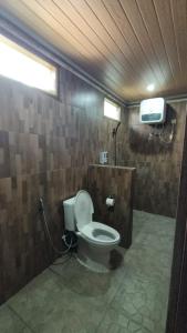a bathroom with a toilet and a tv on the wall at Villa Bella Sembalun in Sembalun Lawang