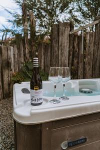 Una botella de vino y dos copas de vino en una bañera. en Raglan Rural Retreats - Rimu Tent, en Raglan