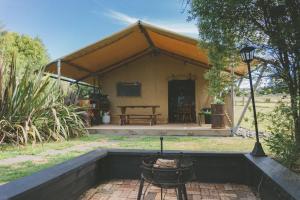 Tienda de campaña con mesa y parrilla en un patio en Raglan Rural Retreats - Rimu Tent, en Raglan