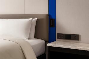 a bedroom with a bed and a clock on a table at Holiday Inn Express Guangzhou Baiyun Airport T2 by IHG in Huadu