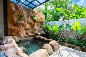 una piscina en un jardín con una pared de roca en Peaceful 1BR Private Villa in Sayan Ubud, en Ubud