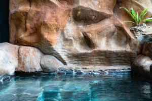 una piscina de agua frente a una pared de roca en Peaceful 1BR Private Villa in Sayan Ubud, en Ubud