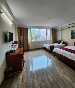 Una habitación de hotel con dos camas y un escritorio. en Phương Thảo Hotel - Near Noi Bai Airport, en Kon Rung (1)