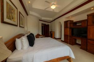 Un dormitorio con una cama blanca y un televisor. en Bella Vista 3A 3BR Ocean View, en Isla Herradura