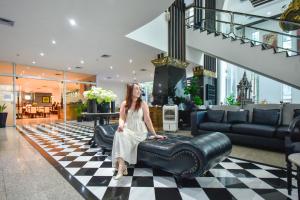 a woman sitting on a leather chair in a lobby at Pinnacle Lumpini Park Hotel in Bangkok