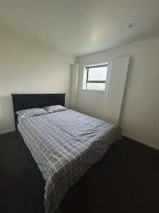 a bedroom with a bed with a plaid blanket and a window at Spacious 3-Bedroom Retreat Near Airport & City in Auckland