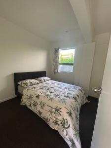 a bedroom with a bed with a comforter and a window at Spacious 3-Bedroom Retreat Near Airport & City in Auckland