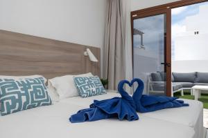 Una cama con dos toallas azules en forma de corazón. en Casa Ancoa, en Playa Blanca