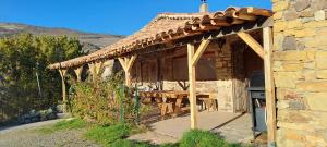 ein Steinhaus mit einer Holzveranda mit einem Tisch in der Unterkunft Gîtes de Saint-Ribert 6 pièces in La Rochette