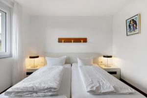 赫汀恩Markgraf Apartments Haus 5的白色客房的两张床,配有两盏灯