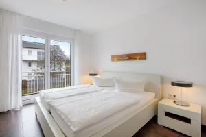 un letto bianco in una stanza con una grande finestra di Markgraf Apartments Haus 2 a Hertingen