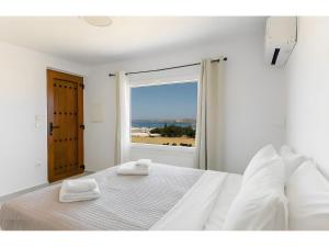 a white bedroom with a bed with two towels on it at Crystal Dream Paros in Ekatondapilianí +138 photos