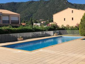 a swimming pool in front of a house with a mountain at Studio Saint Clair pieds dans l'eau in Le Lavandou