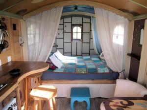 una pequeña habitación con una cama y una mesa en La Roulotte Daninas, en Villeneuve-en-Retz