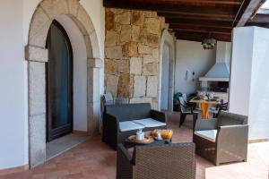 un patio con sedie e tavoli e un muro di pietra di Villa Corallo ad Alghero