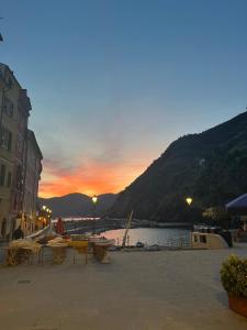 Una playa con mesas y sillas frente a un atardecer. en Roby's Flat, en Vernazza