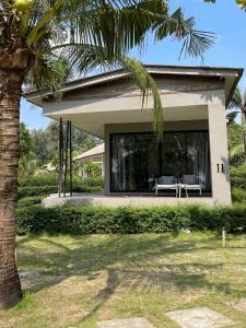 a house with a palm tree in front of it at Cede Boutique Beach Resort in Ko Phayam