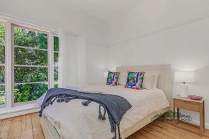 a white bedroom with a bed and a window at Home at Haverfield in Echuca