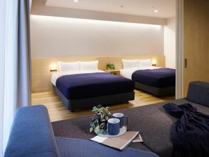 een hotelkamer met 2 bedden en 2 stoelen bij Minn Umeda Nakazakicho in Osaka