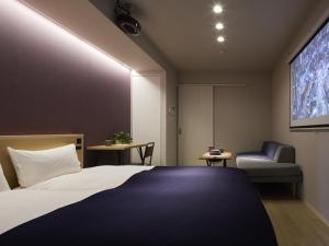 een slaapkamer met een bed, een tv en een stoel bij Minn Umeda Nakazakicho in Osaka