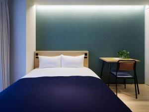 een slaapkamer met een bed en een tafel met een stoel bij Minn Umeda Nakazakicho in Osaka