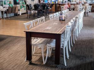 a wooden table with white chairs around it at The Mill Inn Tavern in Millmerran