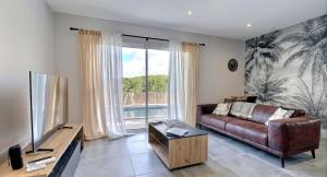 een woonkamer met een leren bank en een groot raam bij Villa Flora in Balazuc