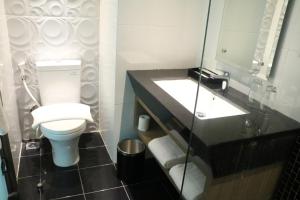 a bathroom with a toilet and a sink at Luminor Hotel Pecenongan Jakarta By WH in Jakarta