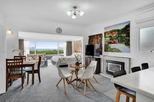 a living room with a table and chairs and a fireplace at No 1 Beachfront Holiday Home in New Plymouth