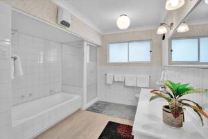 a white bathroom with a tub and a sink at No 1 Beachfront Holiday Home in New Plymouth +39 photos
