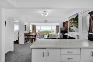 a kitchen and living room with white cabinets and a table at No 1 Beachfront Holiday Home in New Plymouth
