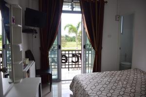 a bedroom with a bed and a balcony with a view at JC Guesthouse @ Suratthani Airport in Surat Thani