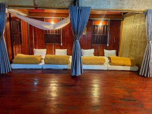 two beds in a room with blue curtains at Nùng An homestay-Nùng ethnic group in Bà Dương